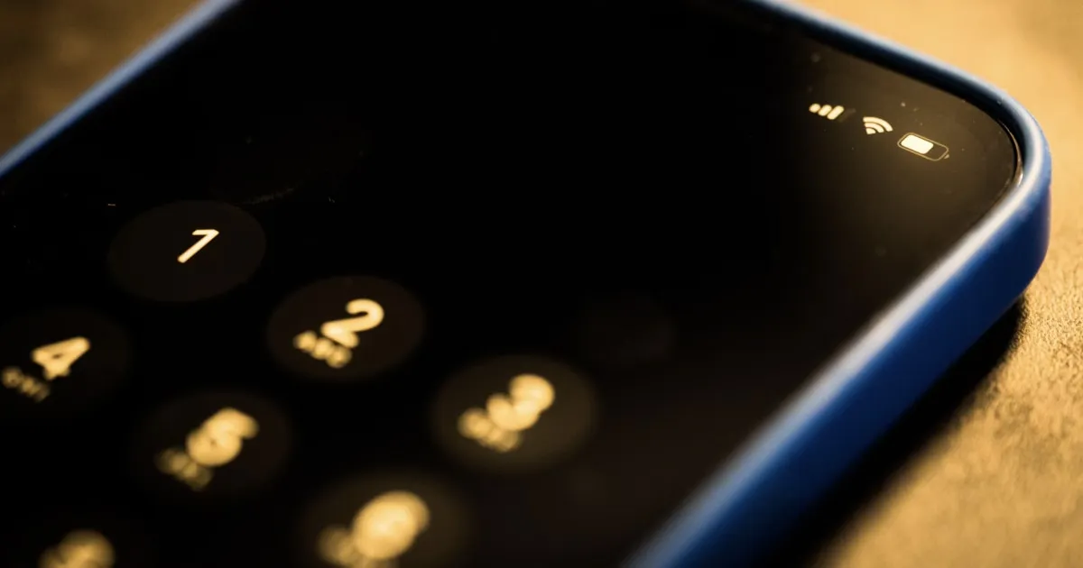 Close-up of an iPhone keypad in the dark, with a blue case.
